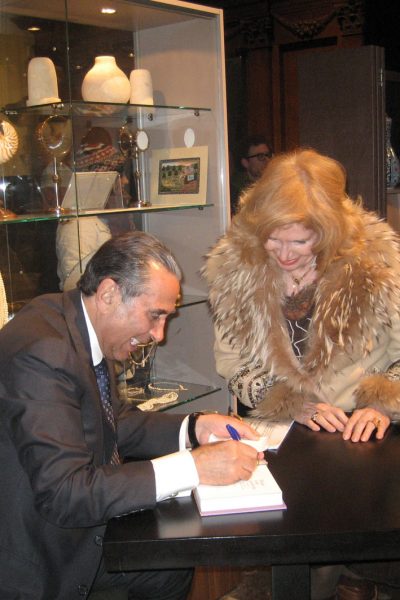 Sir David signing on exhibition catalogue